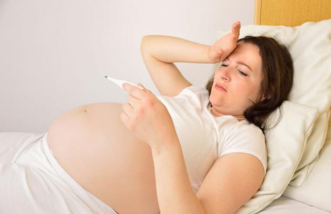 Chica embarazada con termómetro en mano